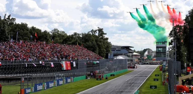 Zuschauertribüne mit italienischen Fahnen und buntem Rauch über dem Rennstreckenkurs.